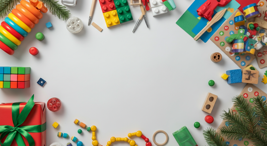 Christmas toys for 5-year-olds arranged around holiday decorations with building blocks, stacking rings, craft supplies, and wrapped gift on white background